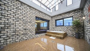 Un intérieur moderne avec des murs en briques apparentes, un plafond en verre et un banc en bois.