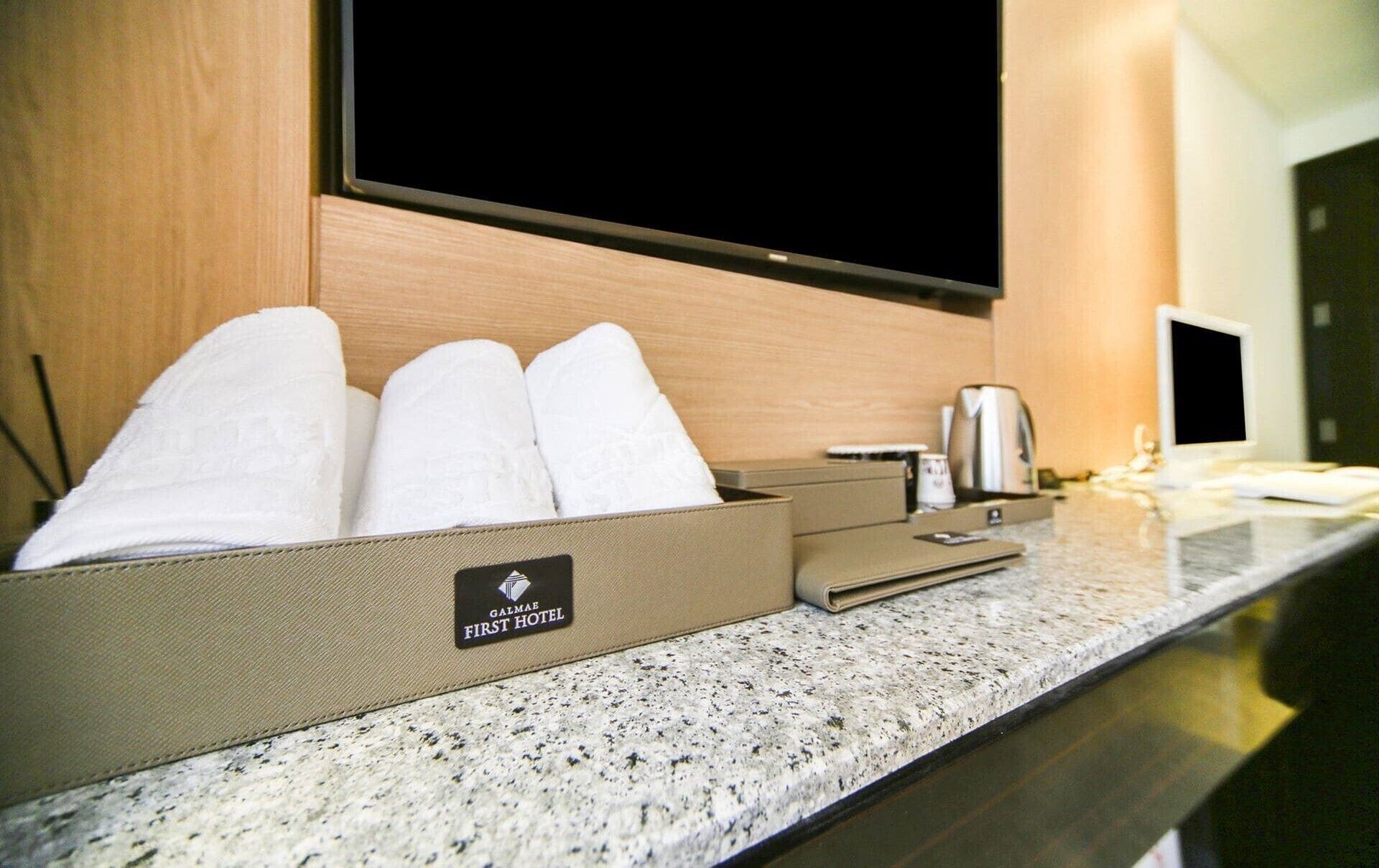 Une chambre d’hôtel équipée d’un téléviseur à écran plat, d’une machine à café et d’un porte-serviettes où les serviettes sont soigneusement pliées.