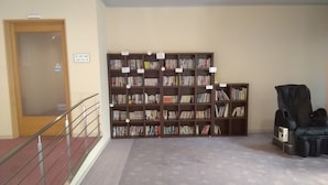 A library with bookshelves, a massage chair, and a staircase. - Hotel Amabile Maizuru (Maizuru)