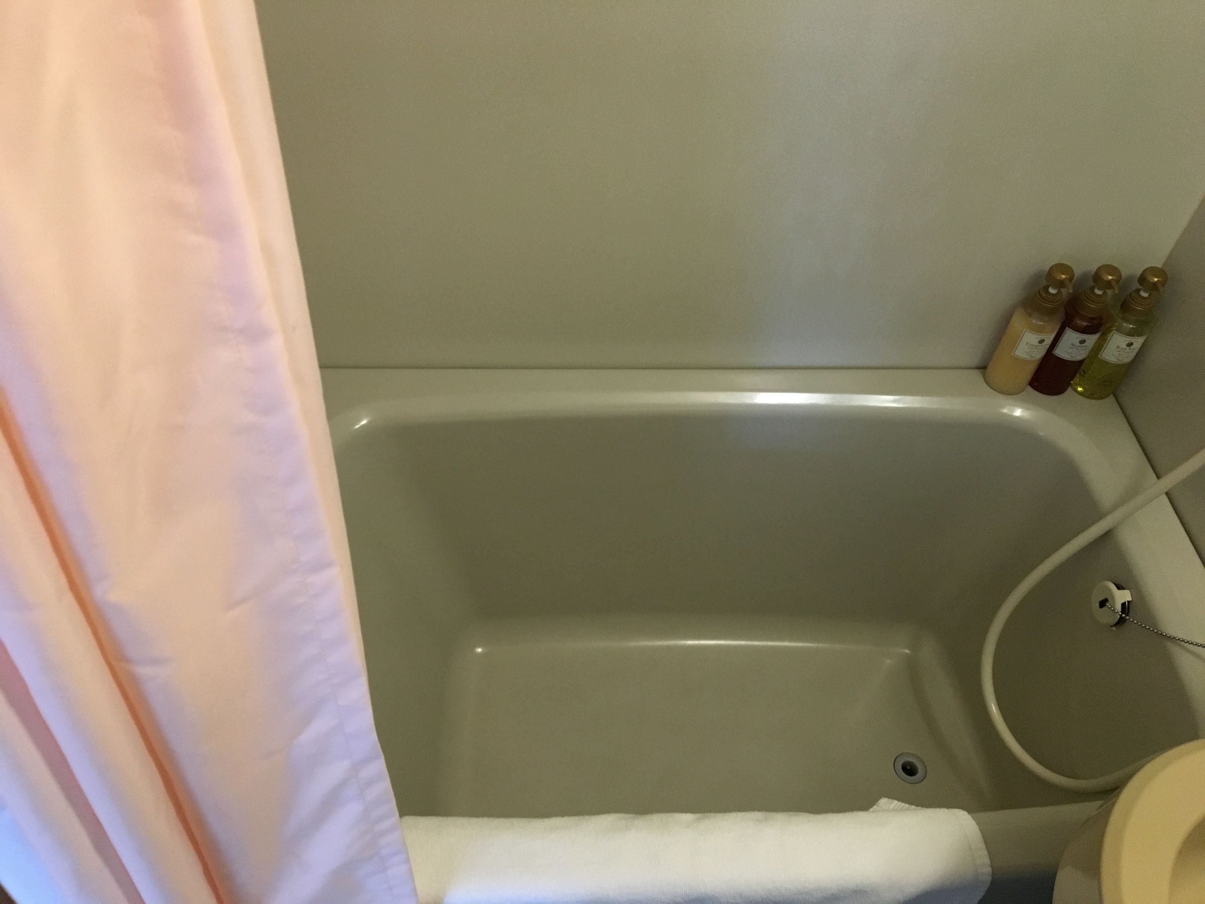 A bathroom with a bathtub, a toilet, and three bottles of liquid on the wall.