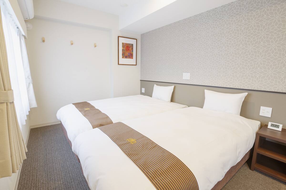 Ein Hotelzimmer mit einem großen Bett, einem Nachttisch, einer Uhr und einem gerahmten Bild an der Wand.