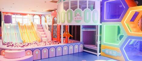 A colorful indoor play area with slides, a ball pit, and various play structures.