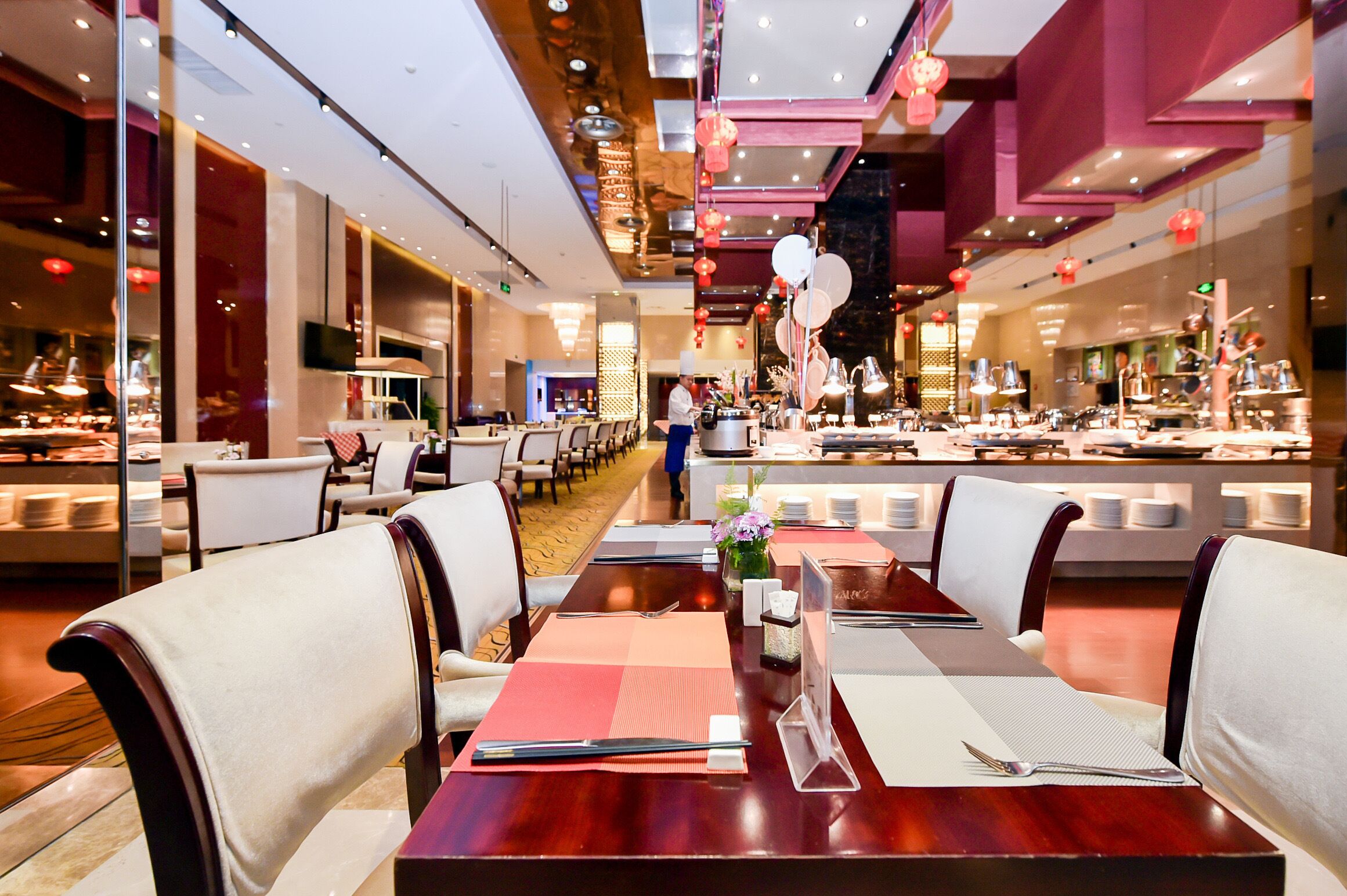A restaurant with a long dining table set for a meal, surrounded by chairs.
