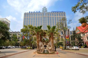 Un hotel con un edificio imponente, palme e una fontana sullo sfondo.