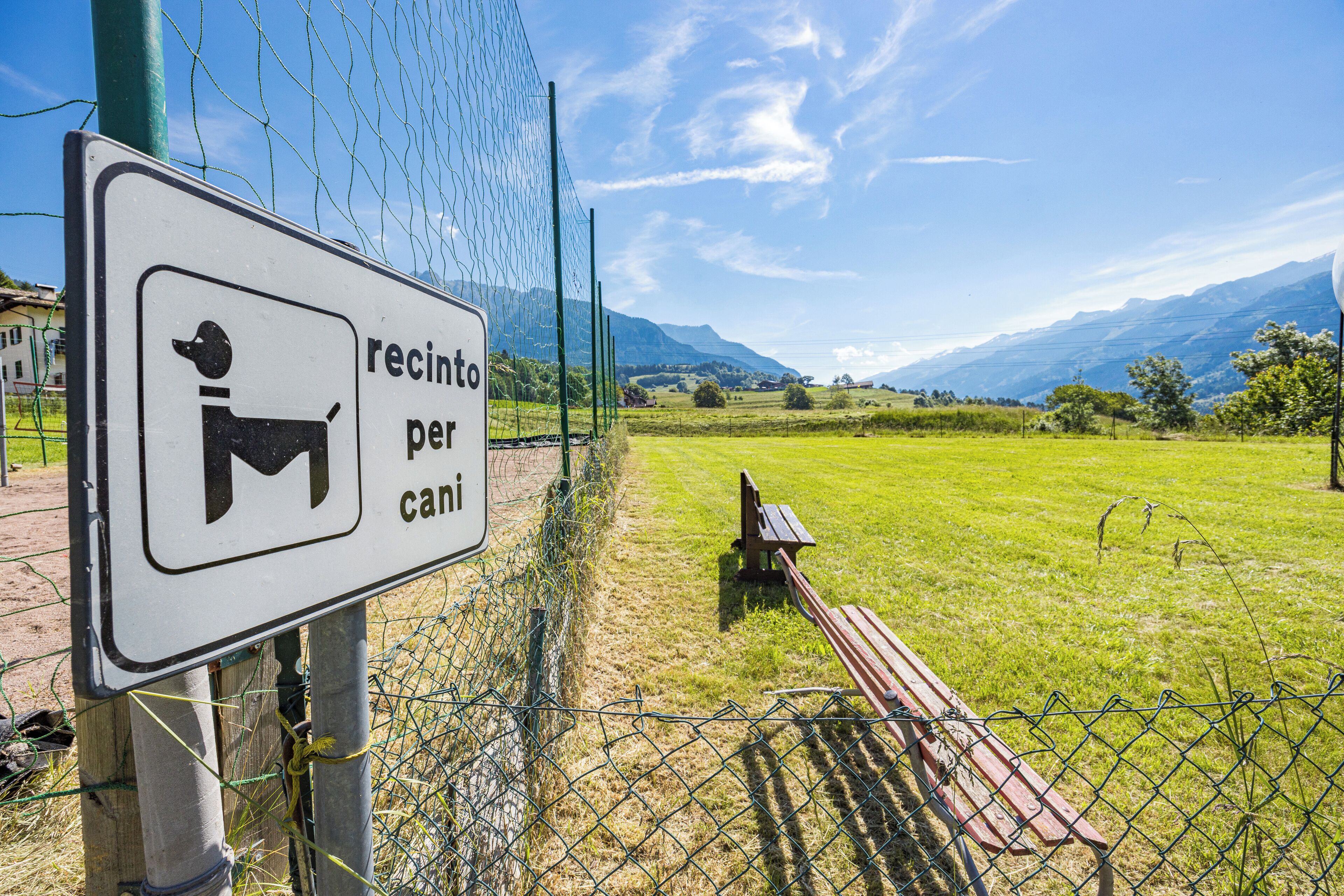 Un cartel con el símbolo de un perro y el texto 'recinto per cani', que indica una zona para perros.