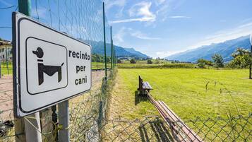 Un cartel con el símbolo de un perro y el texto 'recinto per cani', que indica una zona para perros.