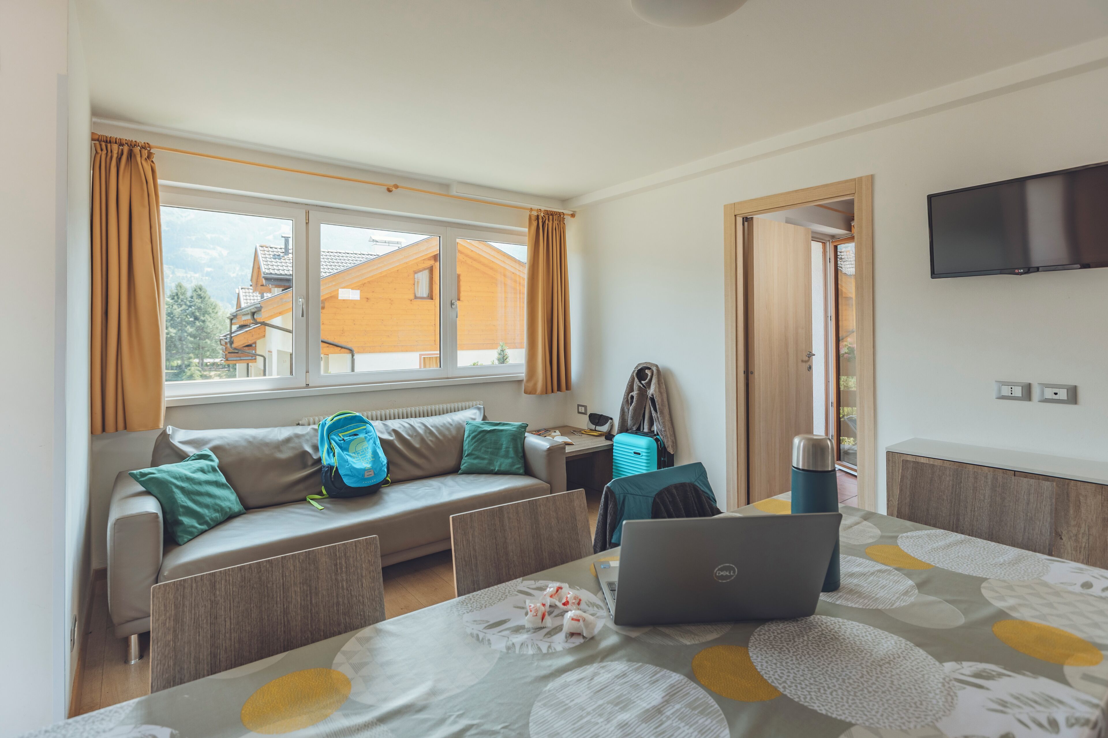 Una habitación moderna con sofá, una mesa con una computadora portátil, una maleta y un radiador.
