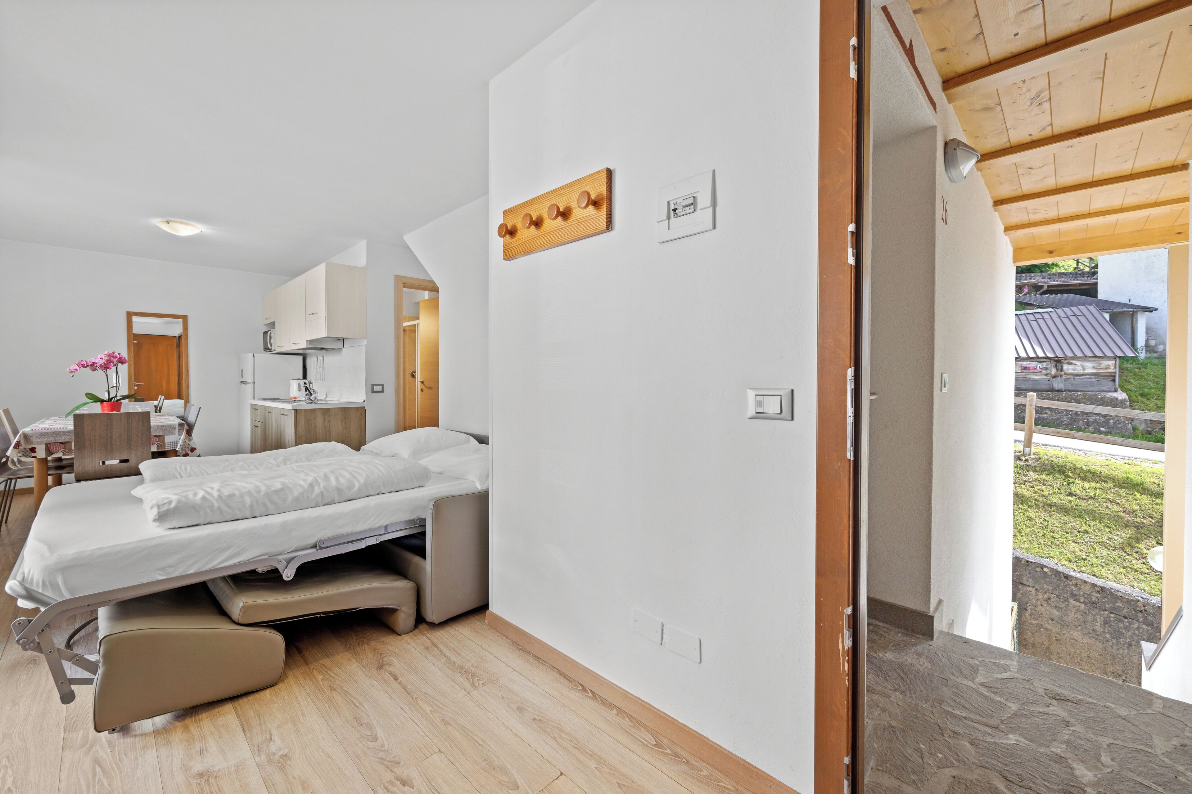 A bedroom with a bed, a desk, and a chair. There is a window with a view of the outside.
