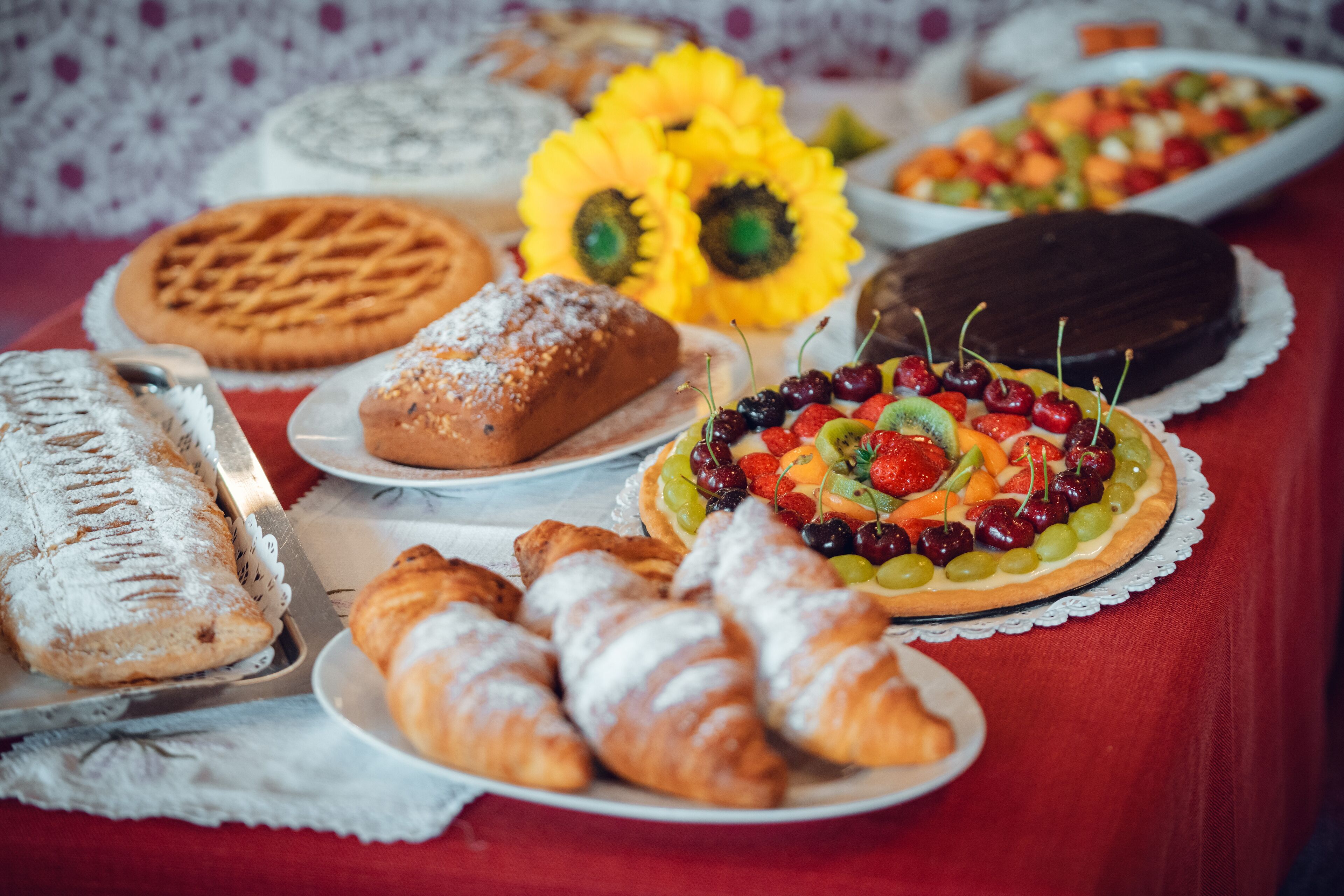A variety of desserts including a chocolate cake, a fruit tart, and pastries on a table.