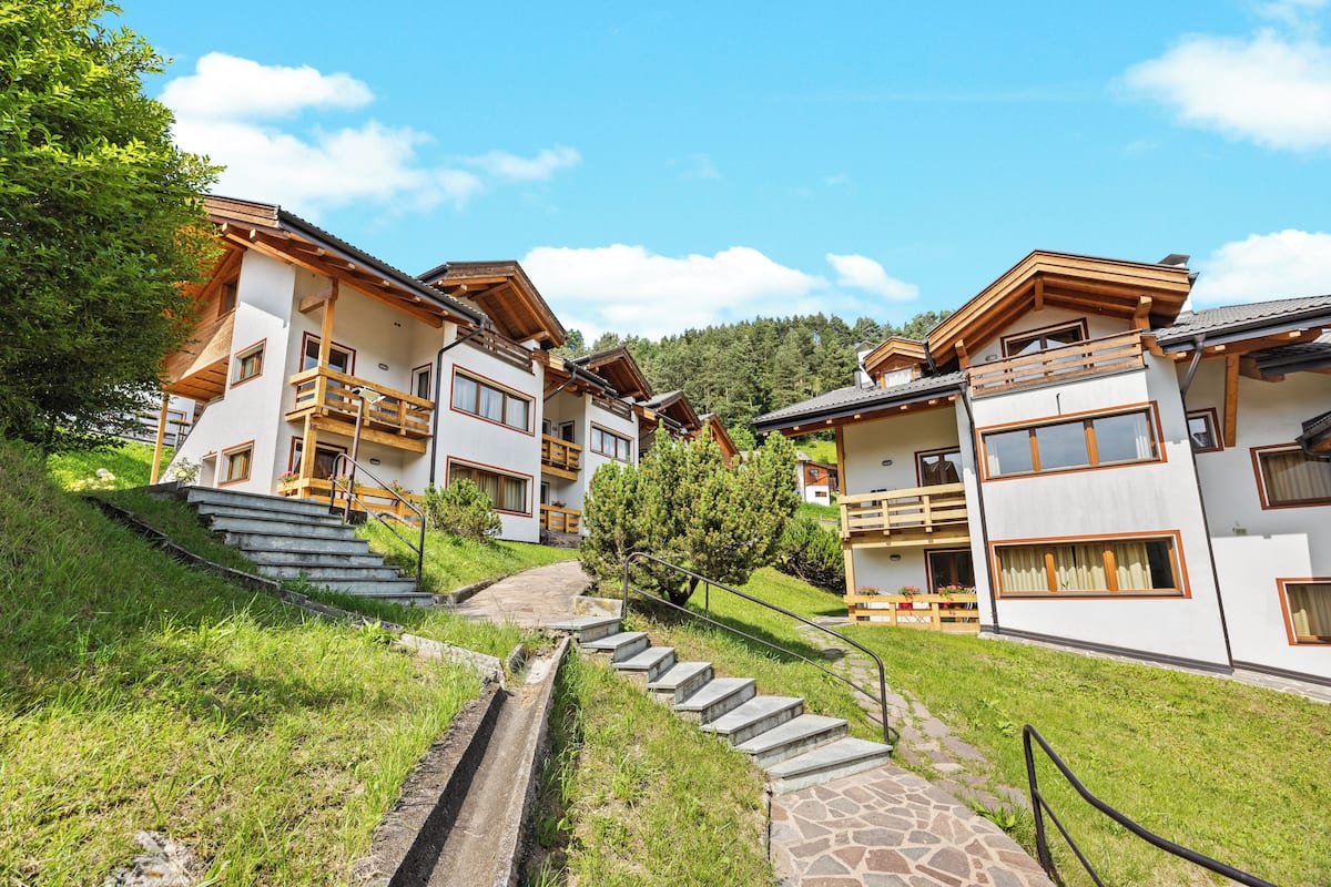 A hillside hotel with multiple buildings, stone staircases, and a small stream.