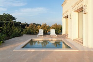 Uma área de piscina com duas espreguiçadeiras e um edifício com grandes janelas.