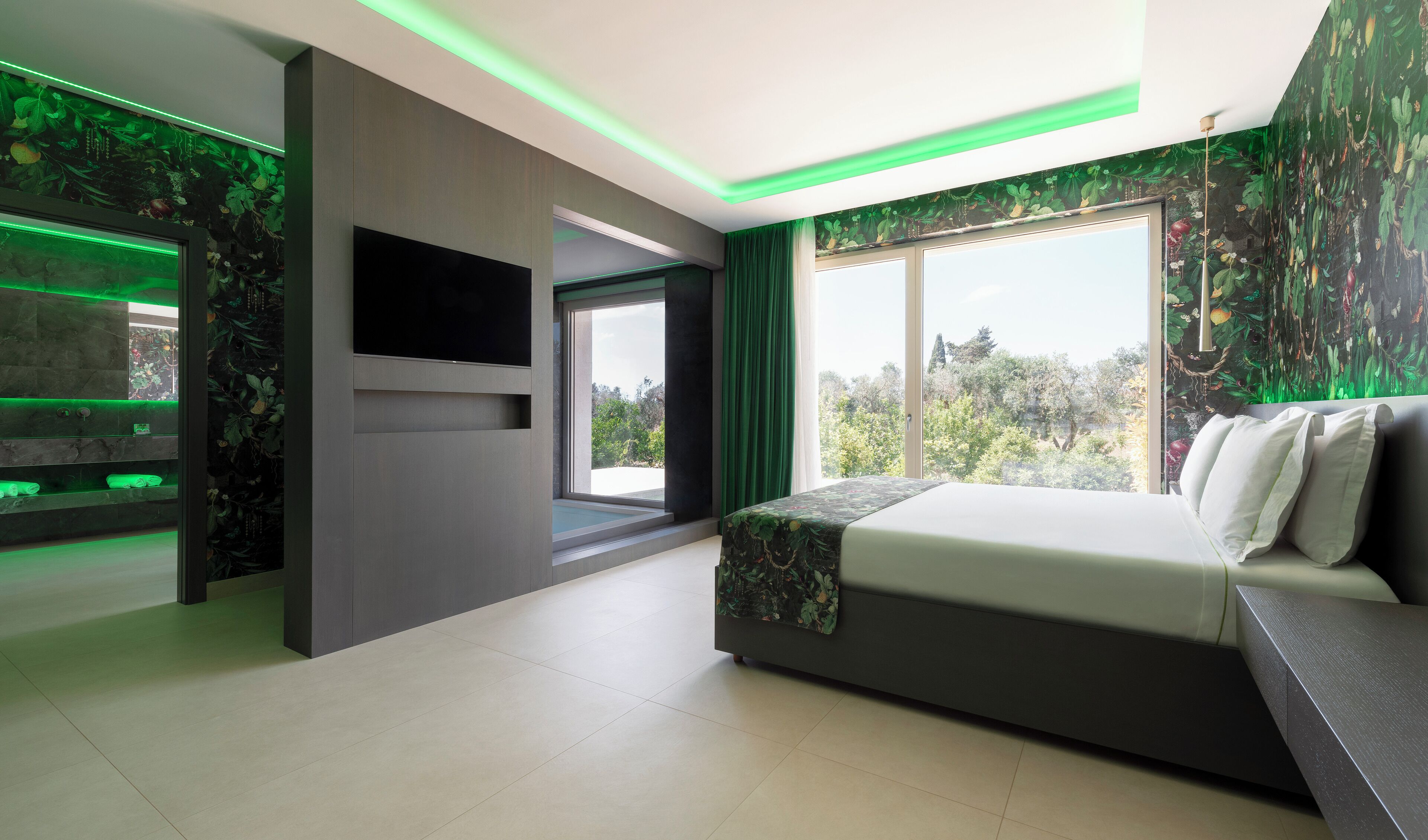 Une chambre moderne avec un grand lit, un téléviseur et un aquarium éclairé de lumière verte.