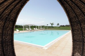 Piscina com espreguiçadeiras e uma estrutura de pérgola.