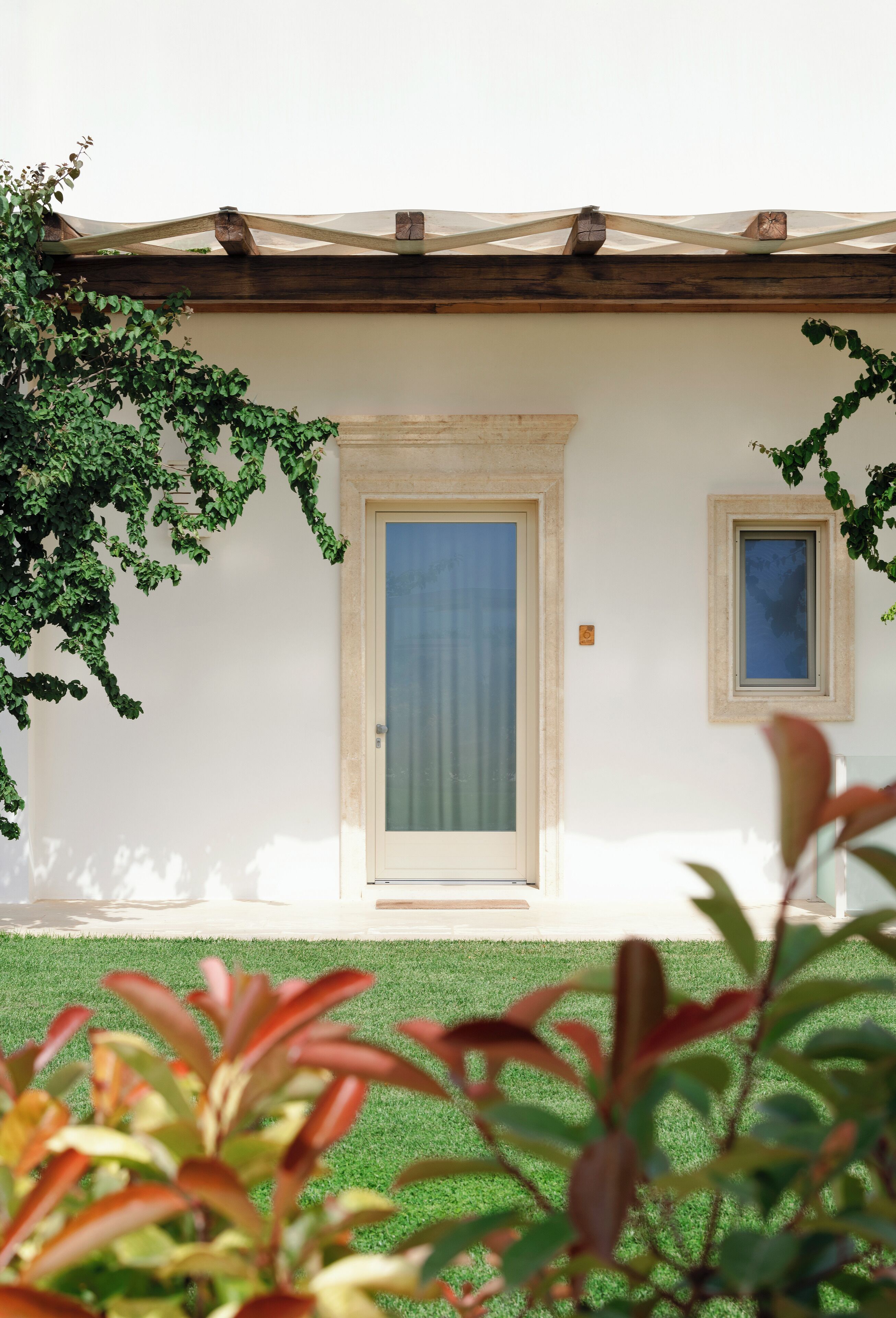 Un edificio con una puerta y una ventana, rodeado de follaje.