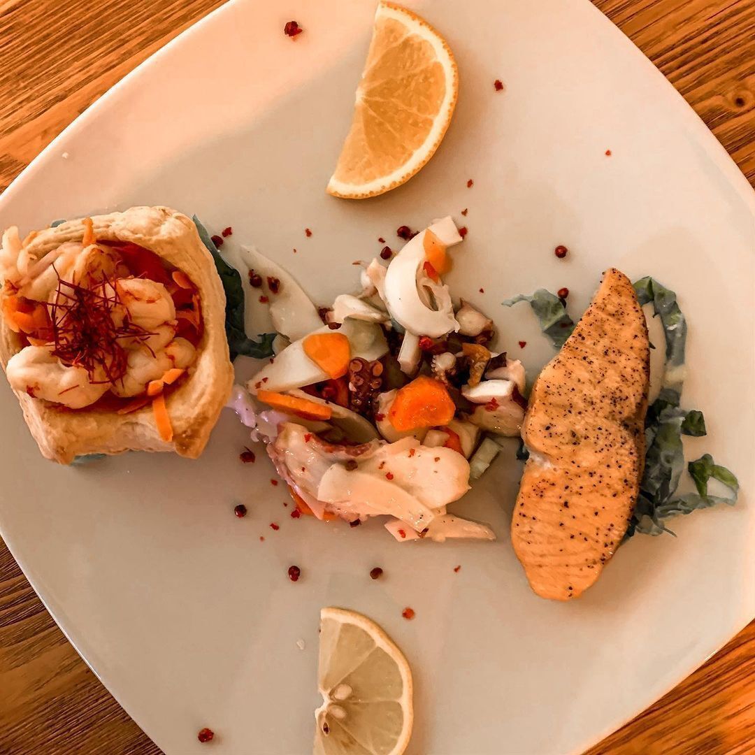 A plate with a salmon fillet, a seafood tart, and a salad.