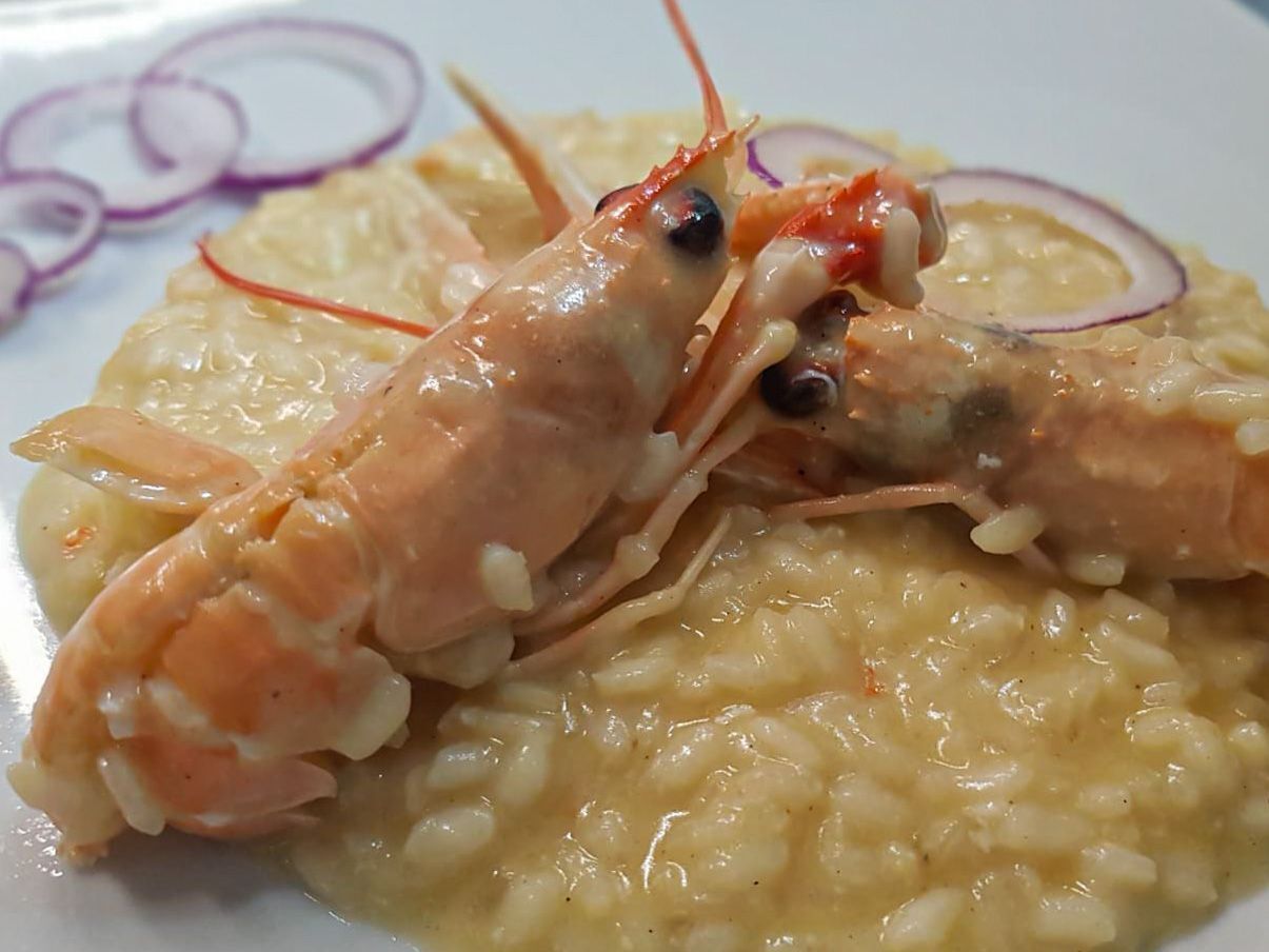 A plate with two cooked lobsters and a serving of risotto.