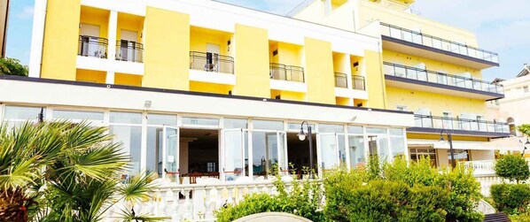 A multi-story hotel with balconies and a covered outdoor seating area. - Hotel Royal (Cattolica)