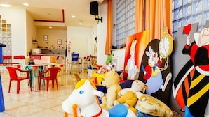 A children's play area with colorful chairs, a white horse ride-on toy, and a wall decorated with cartoon characters. - Hotel Royal (Cattolica)