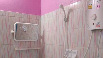 Casa de banho com parede de azulejos listrada em rosa e branco, uma pia branca, um chuveiro manual e um termoacumulador.