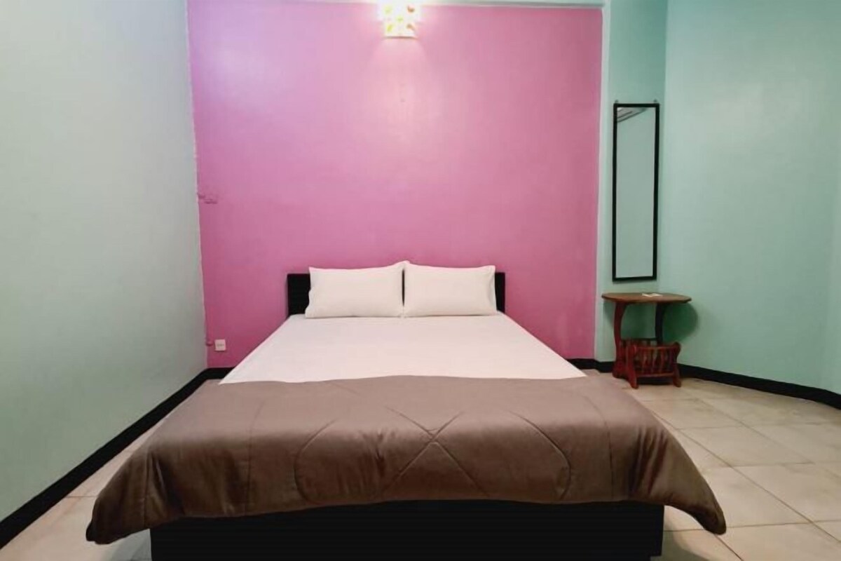 Un dormitorio con una cama, una mesita de noche y un espejo en la pared.