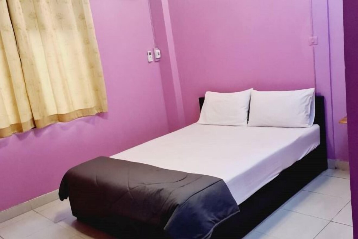A single bed with white bedding in a room with purple walls.