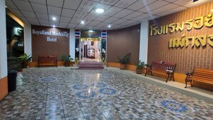 A hotel lobby with a tiled floor, benches, and a sign for the Royalland Maeklong Hotel. - Royal Land Mae Klong Hotel (Samut Songkhram)