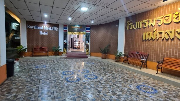 A hotel lobby with a tiled floor, benches, and a sign for the Royalland Maeklong Hotel. - Royal Land Mae Klong Hotel (Samut Songkhram)