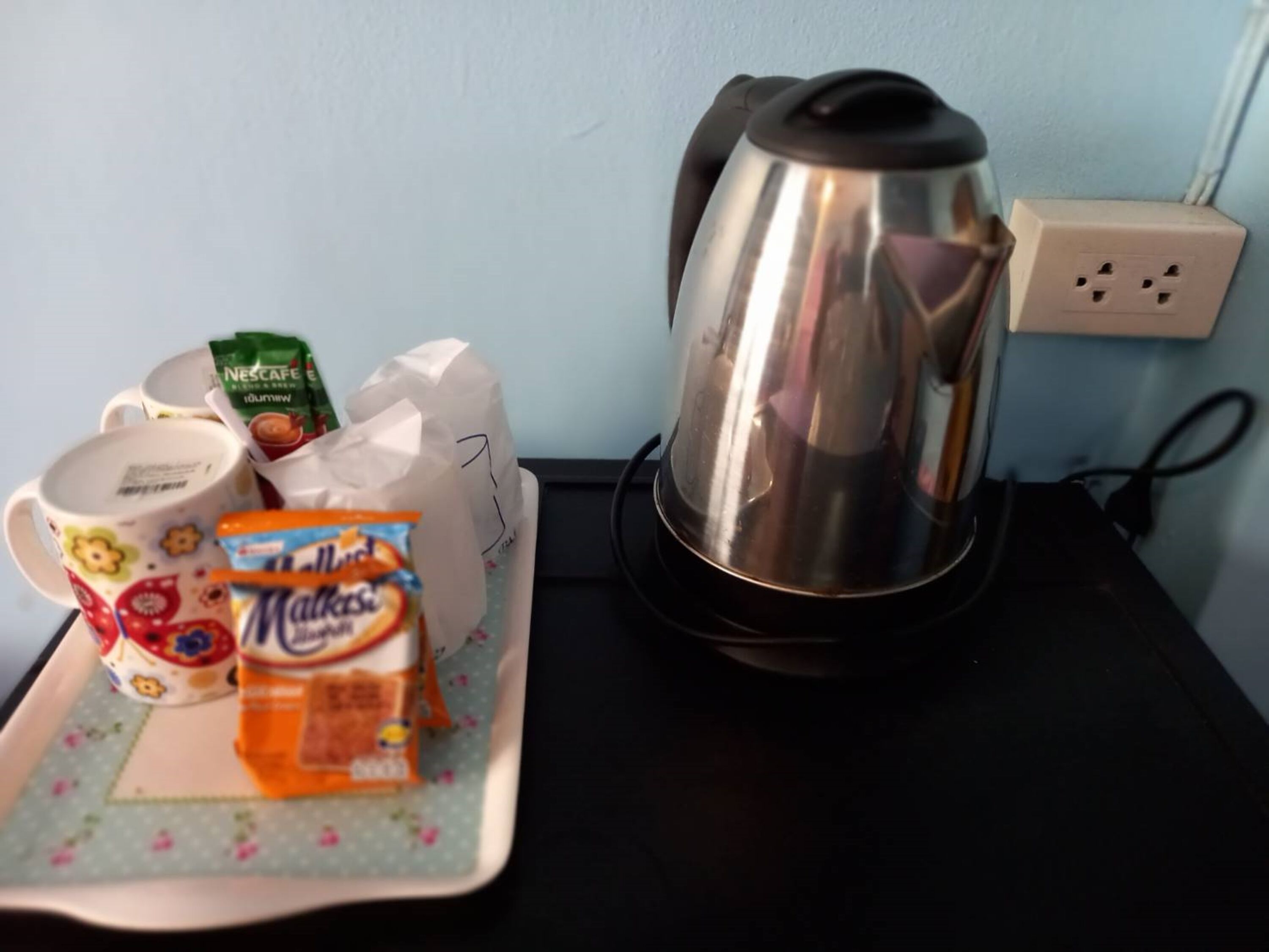 Een keukentafel met een koffiezetapparaat, een mok, een pak melk en een suikerzakje.