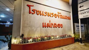 A hotel entrance with a sign in Thai and English, a decorative railing, and potted plants. - Royal Land Mae Klong Hotel (Samut Songkhram)