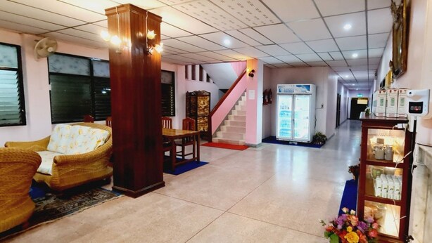 A hotel lobby with a reception desk, a staircase, and a seating area with chairs and a sofa. - Royal Land Mae Klong Hotel (Samut Songkhram)