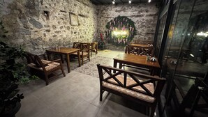A cozy indoor seating area with stone walls, wooden tables, and chairs. - Pergamon Pension (Bergama)