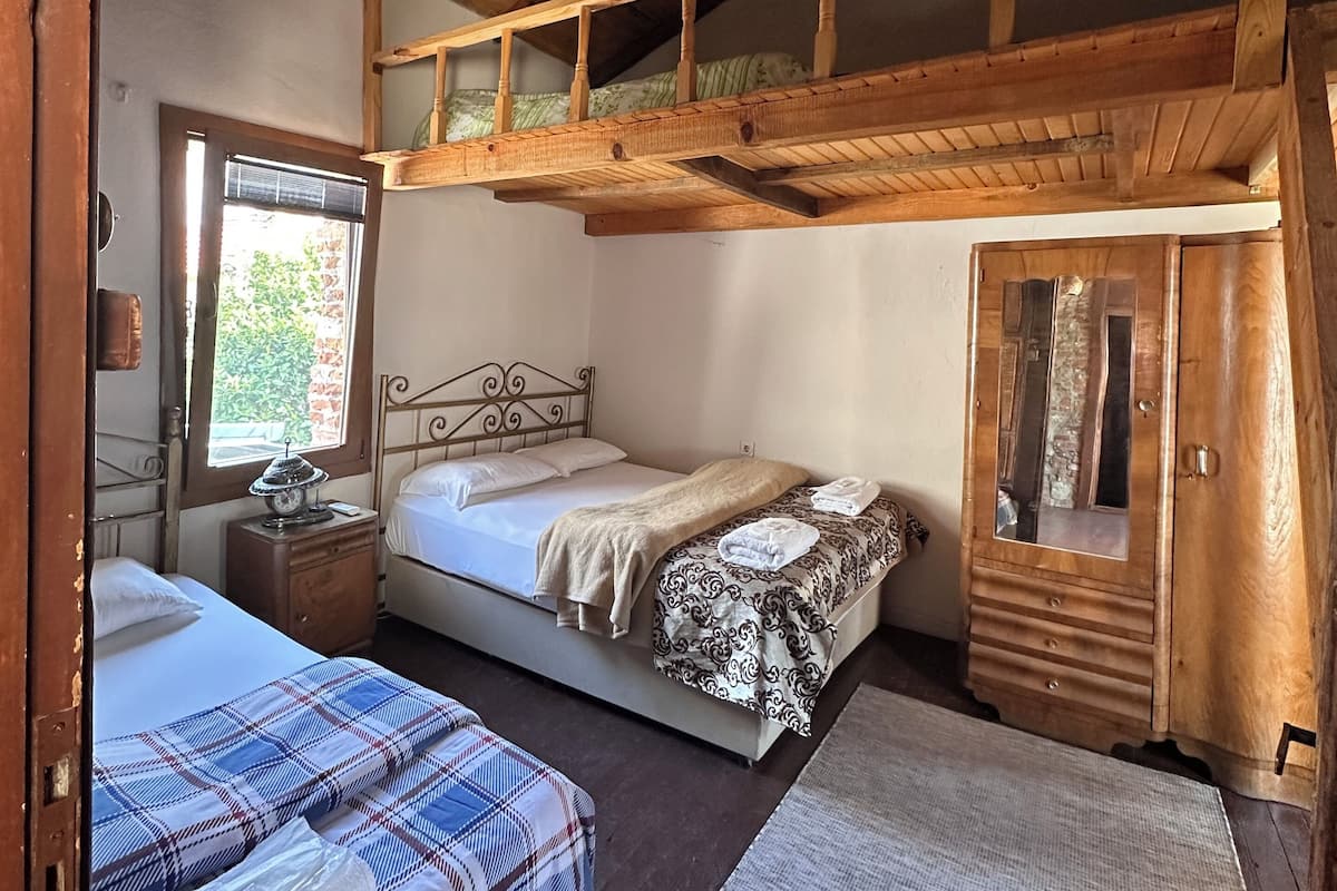 Ein Zimmer mit Hochlaggerl, einem Bett unten, einem Kleiderschrank und einem Fenster mit Blick.