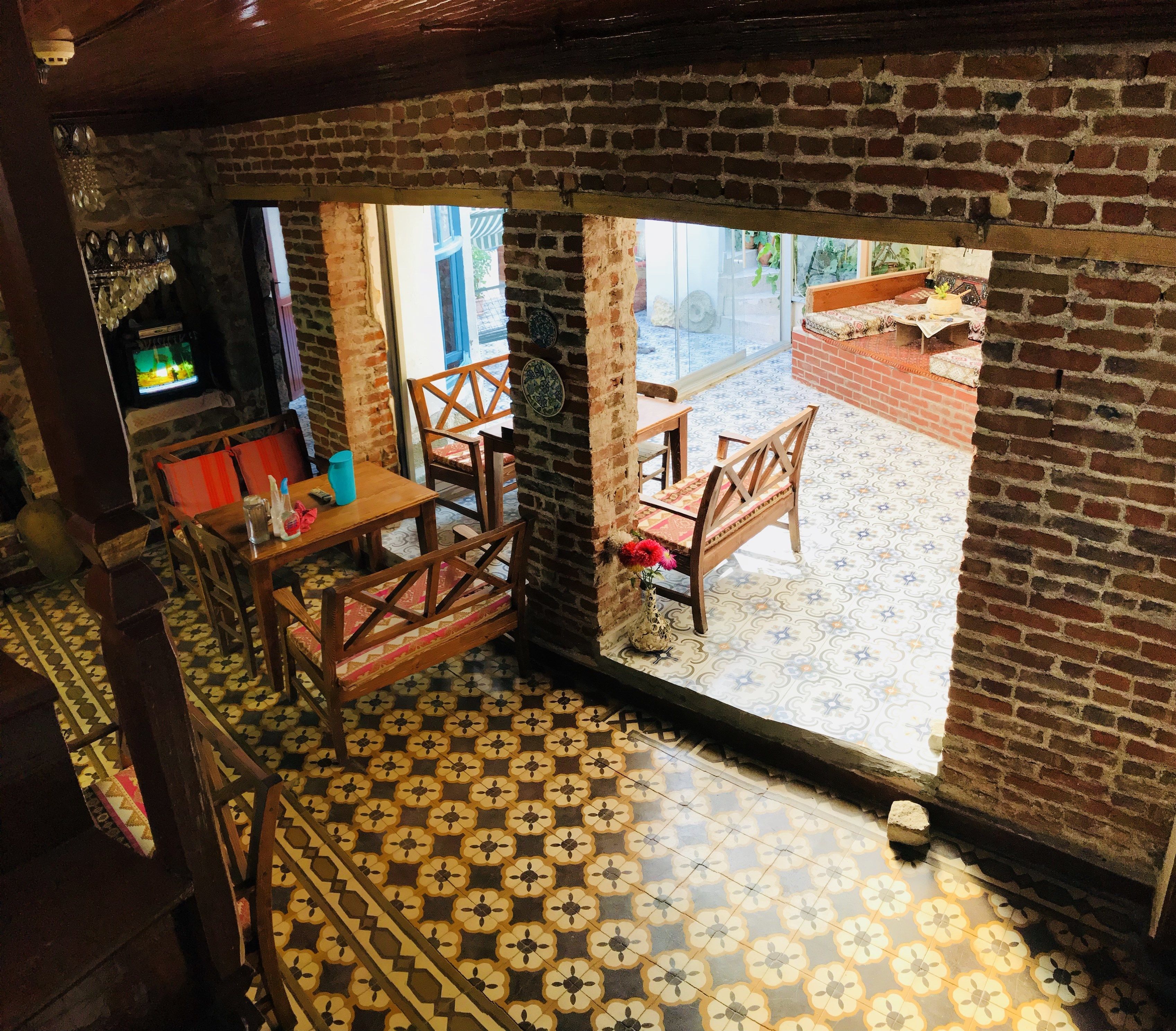 A cozy room with a brick wall, a wooden table, and a patterned floor.