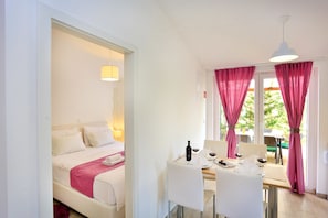 Une chambre d’hôtel avec un lit, une table à manger avec des chaises et des rideaux roses.