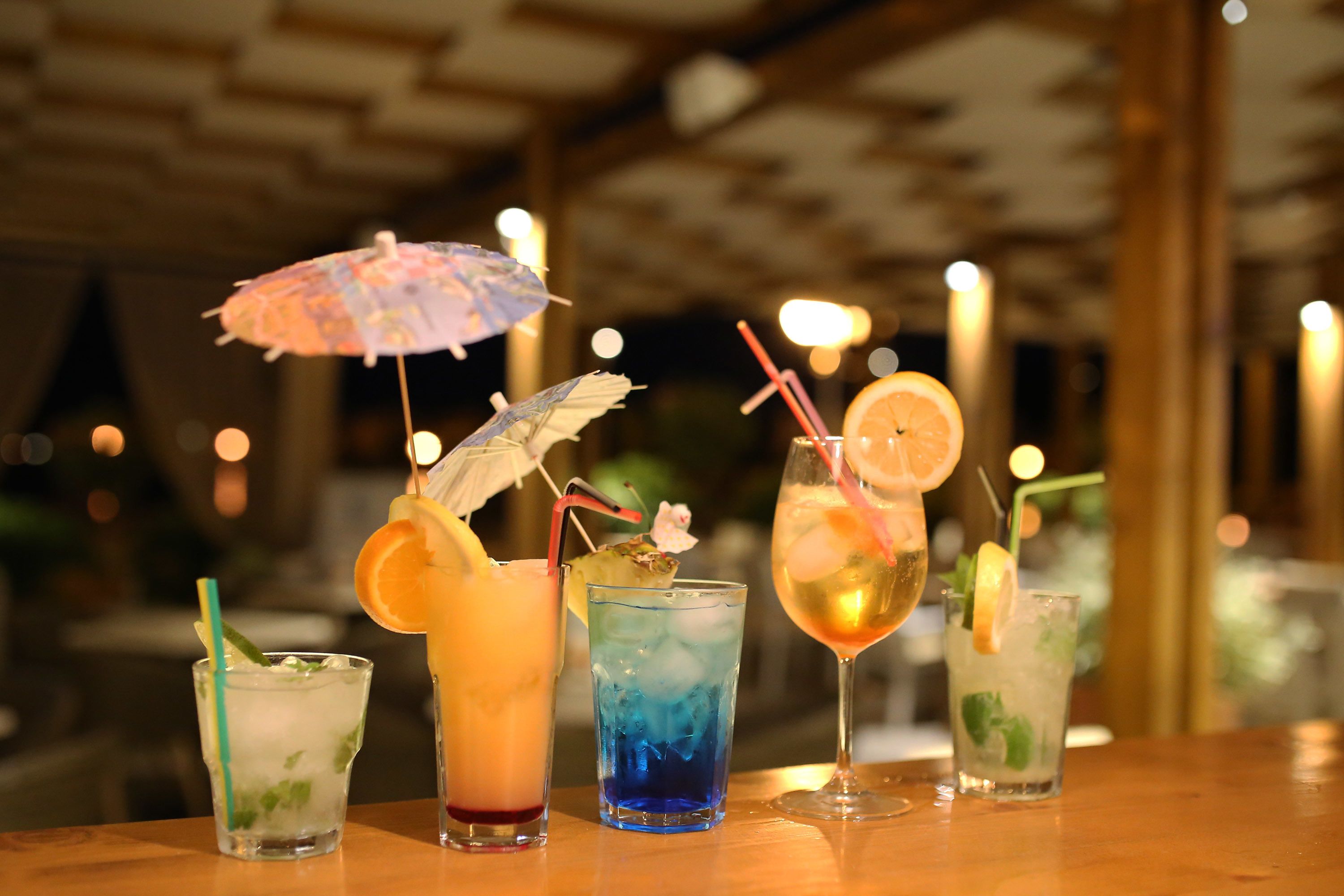 A bar area with various cocktails, each garnished with fruits and straws.