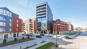 A modern building with multiple floors, a parking lot, and a clear sky. - NORDBYHUS Apartamenty Chmielna Park (Gdansk)