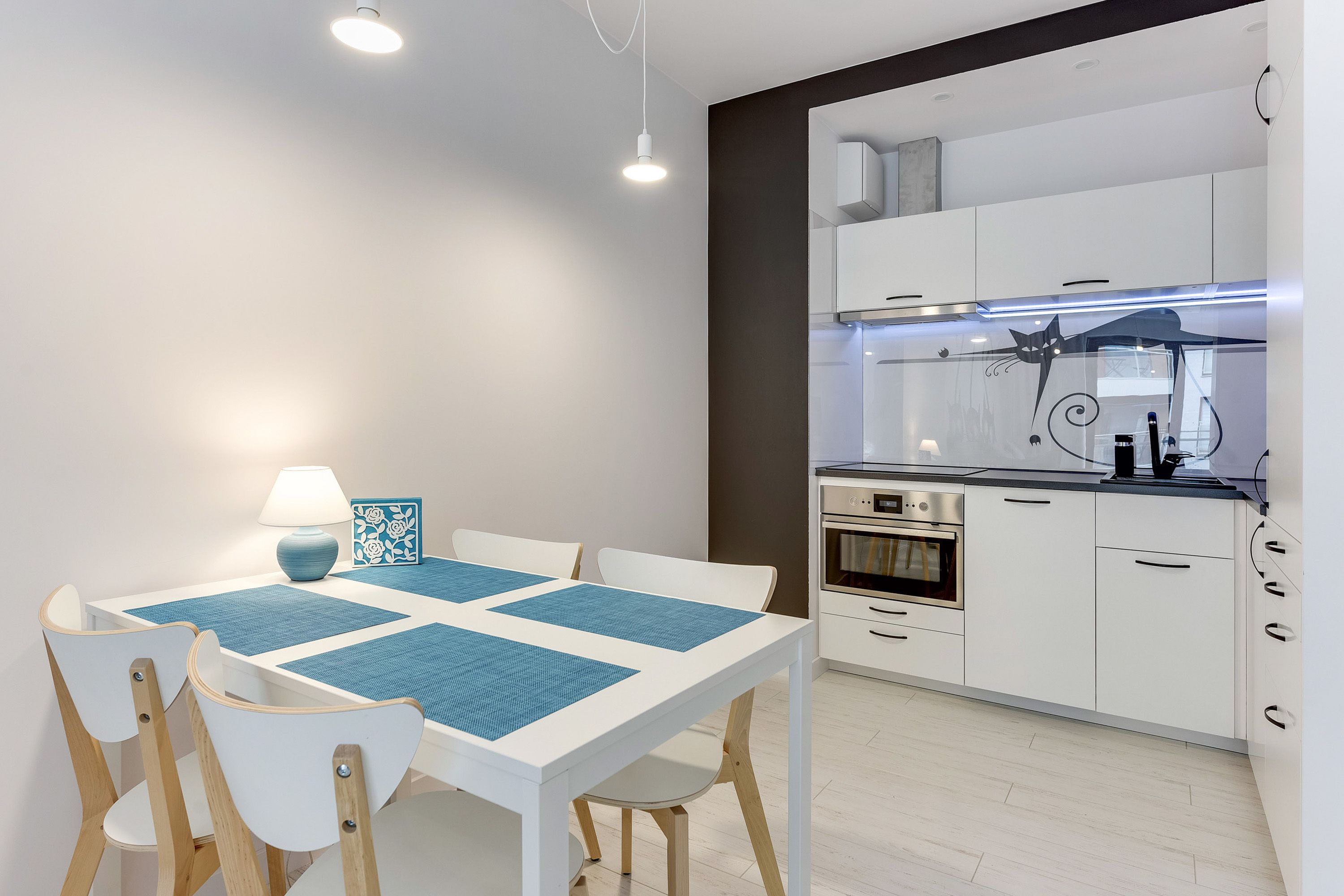 Cozinha moderna com armários brancos, bancada preta e forno embutido.