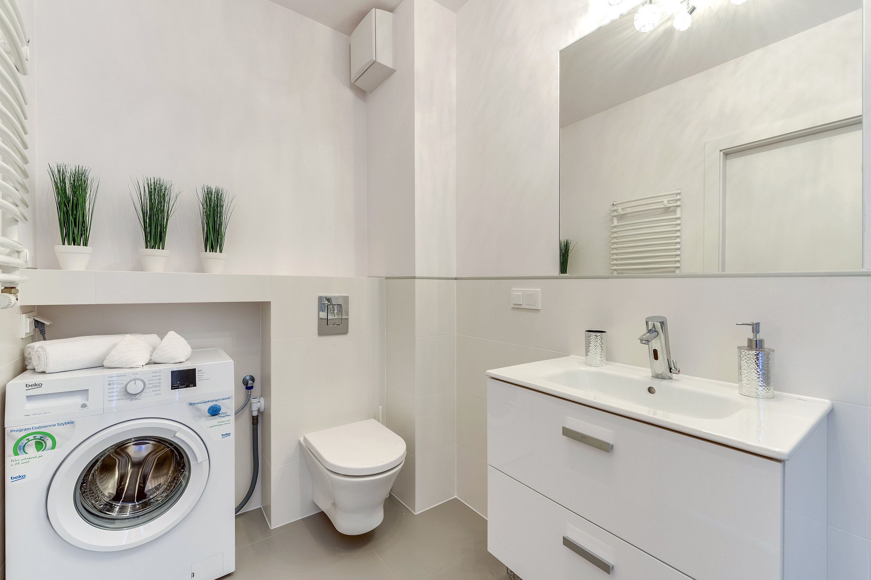 Un baño moderno con lavadora, inodoro y lavamanos con espejo.