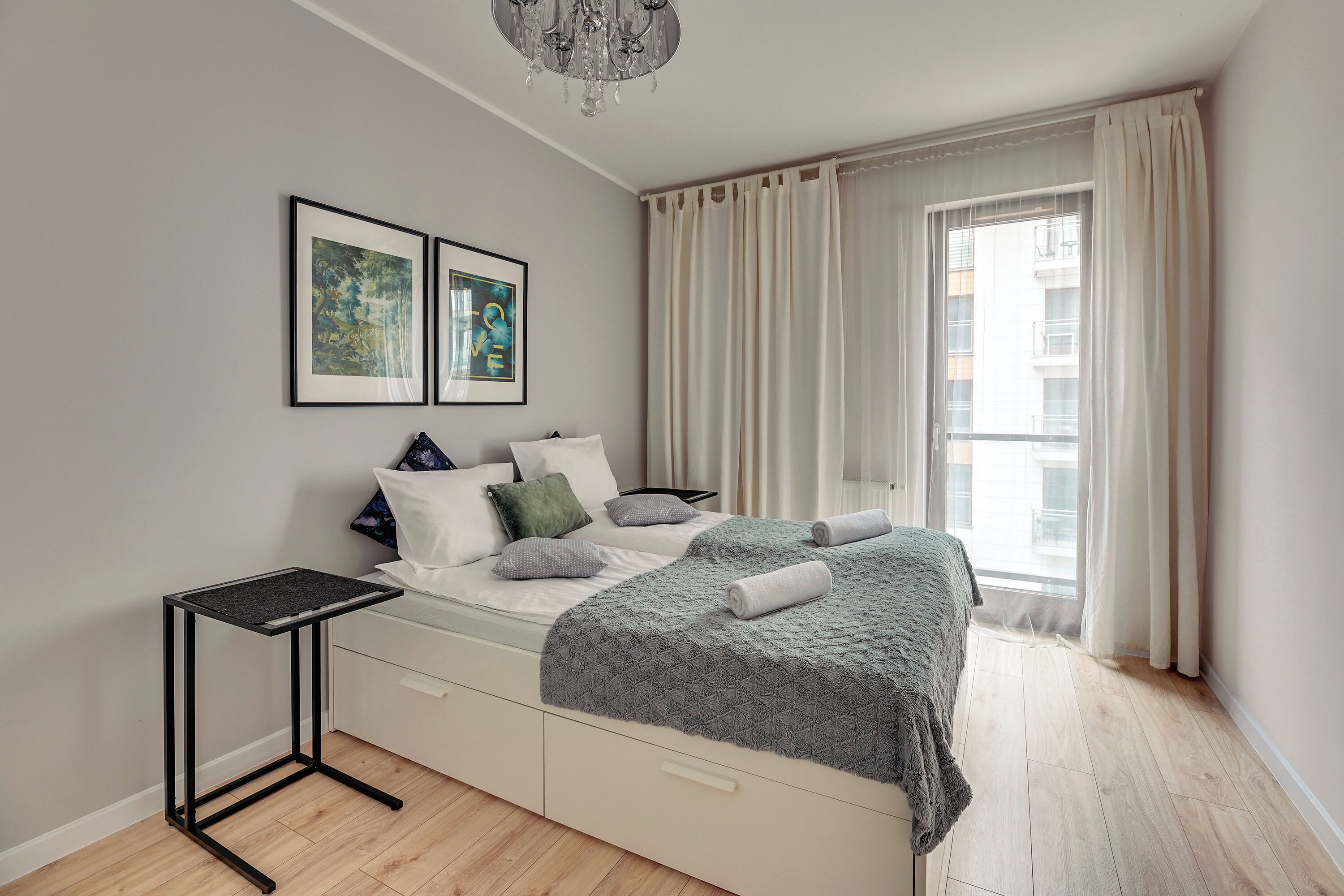 Une chambre bien rangée, avec un lit, des tables de chevet et une fenêtre avec des rideaux.