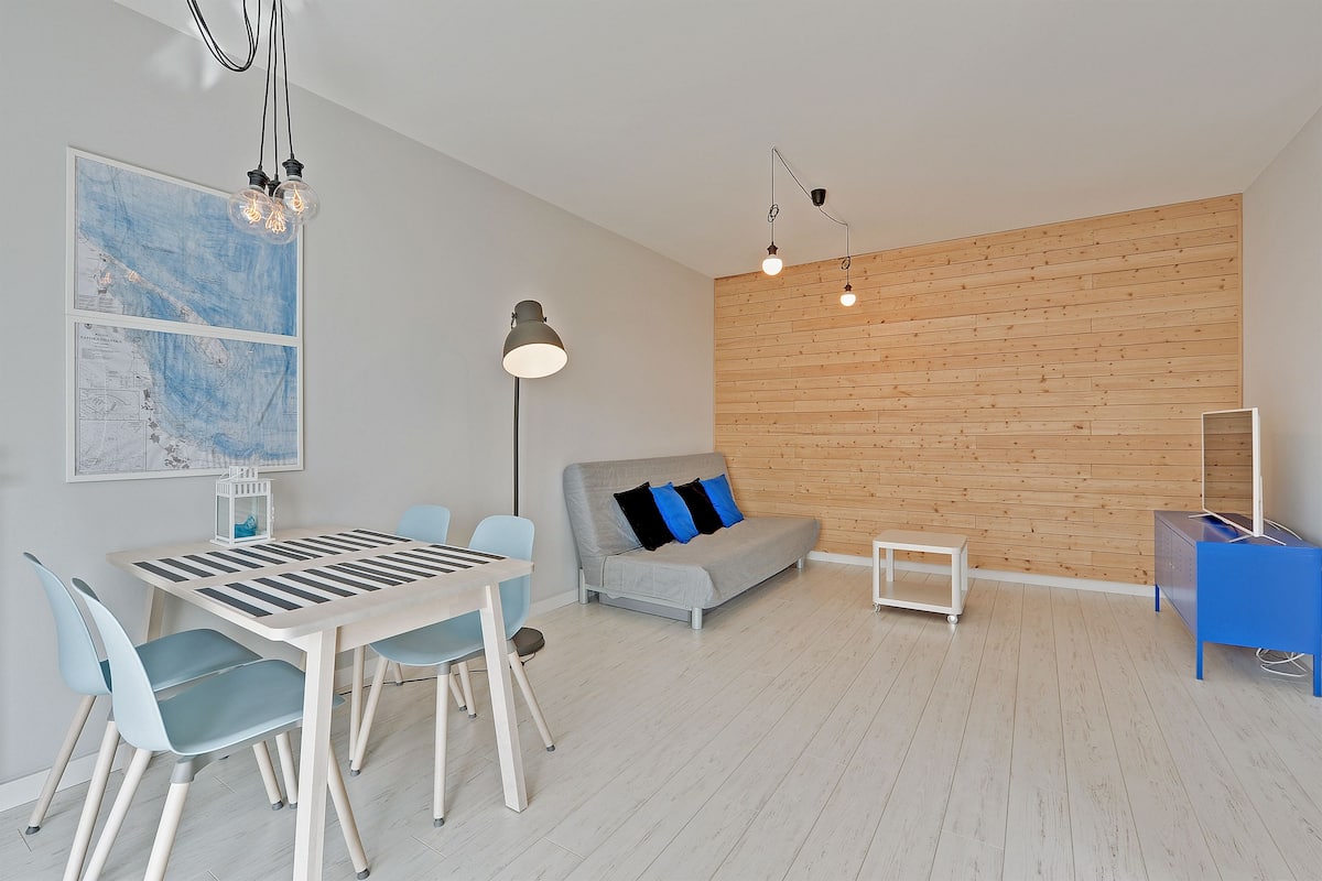 Een moderne woonkamer met een eetgedeelte, een wand van houten panelen en een blauwe kast.
