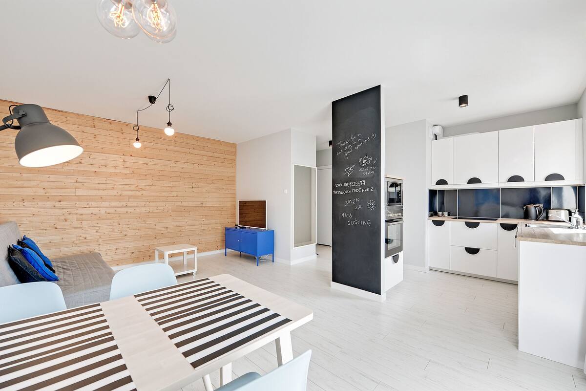 Een modern interieur met een eethoek, keuken en een prikbord met berichten.