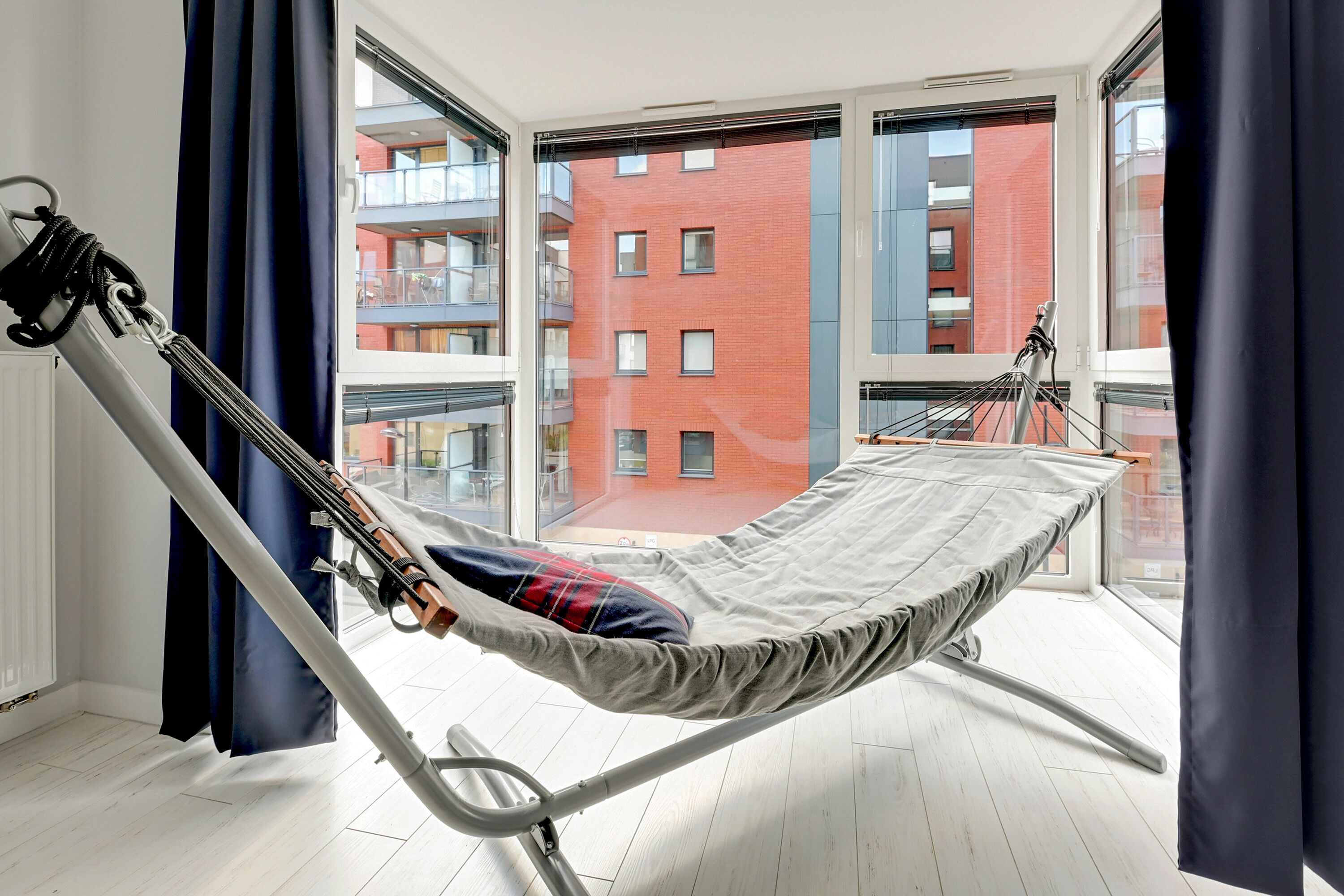 Ein Balkon mit einer Hängematte und Blick auf ein rotes Backsteinhaus.