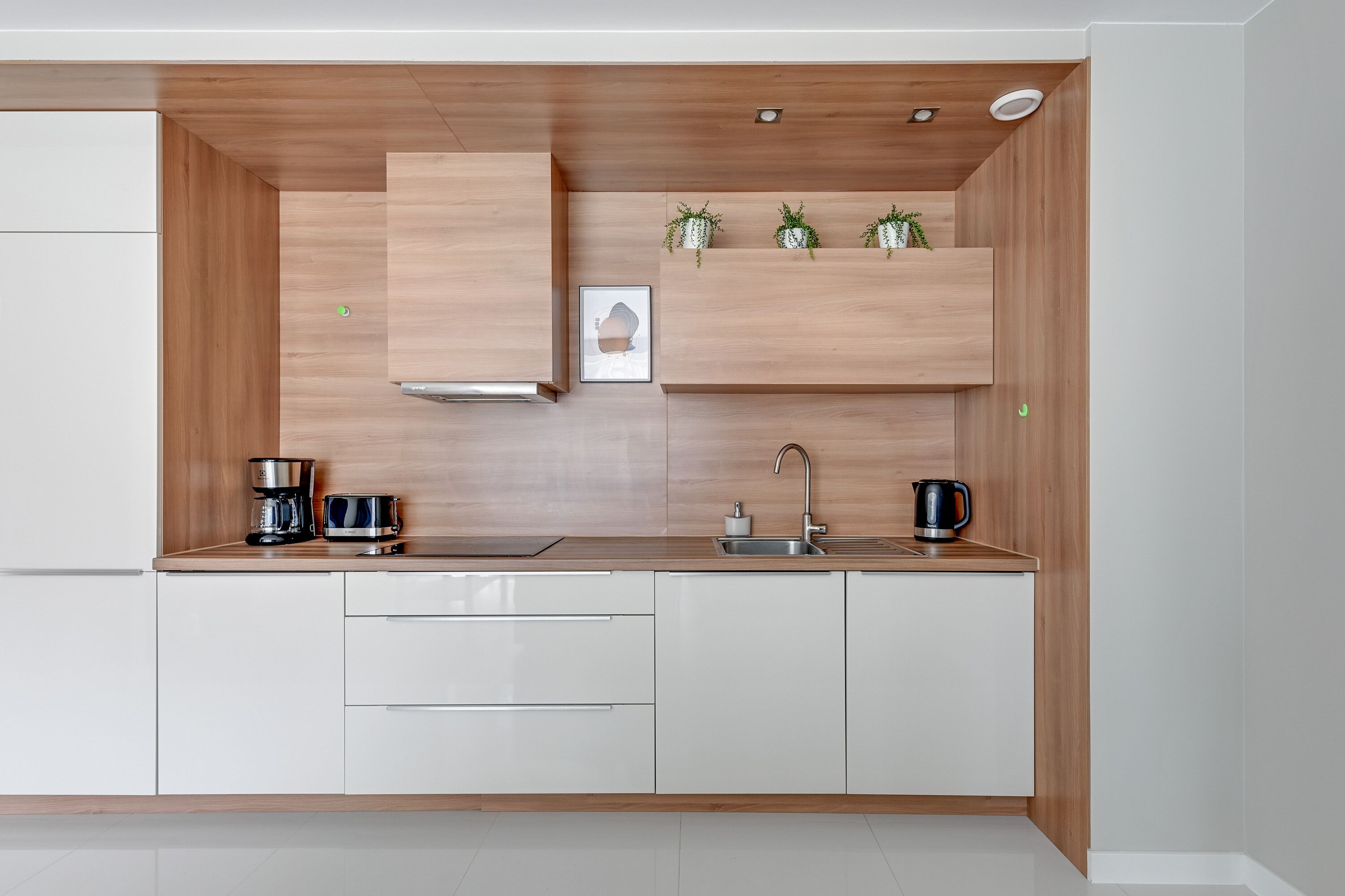 Une cuisine moderne avec des meubles en bois, un évier en acier inoxydable et une machine à café.