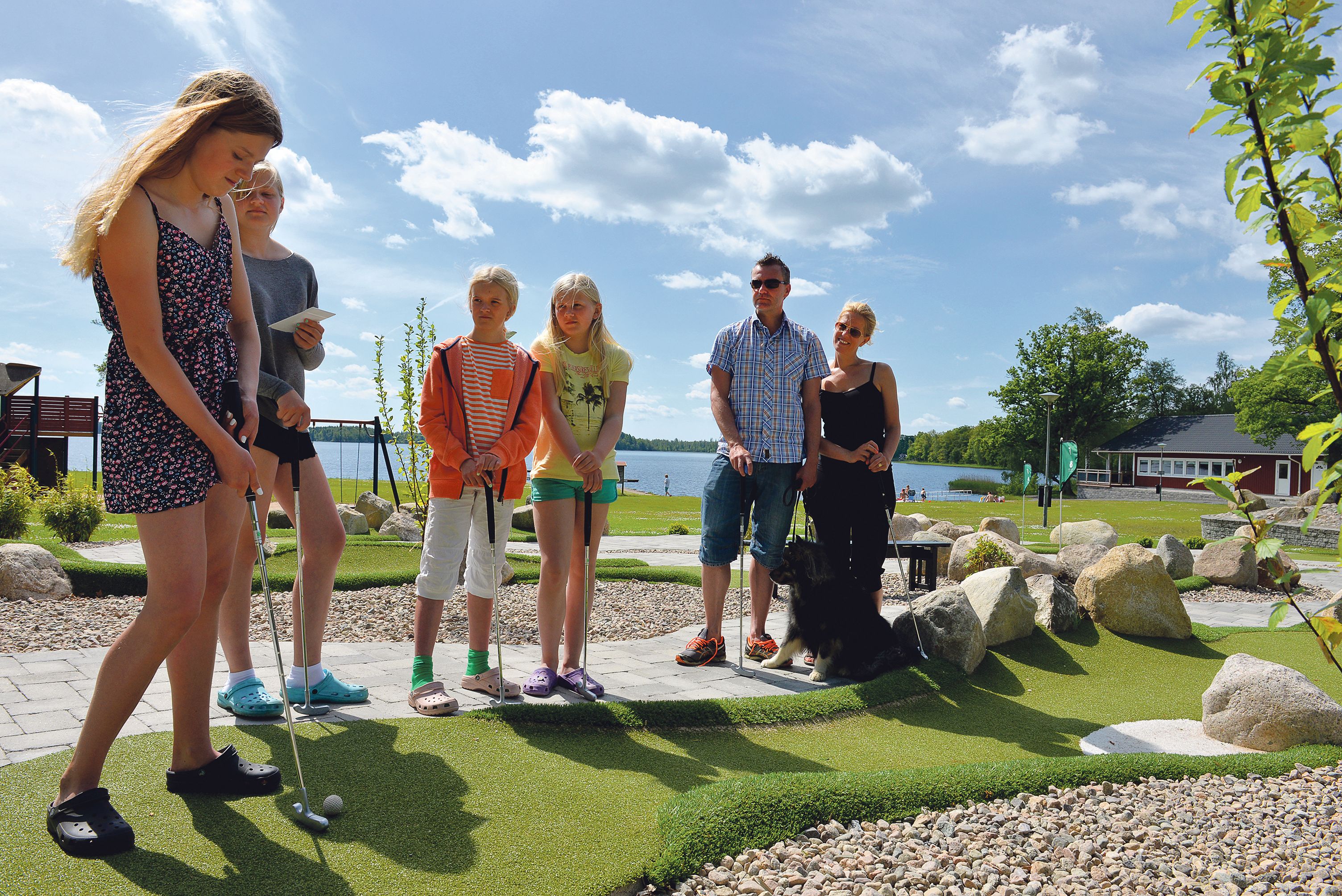Un groupe de personnes jouant au golf sur un parcours avec un lac en arrière-plan.