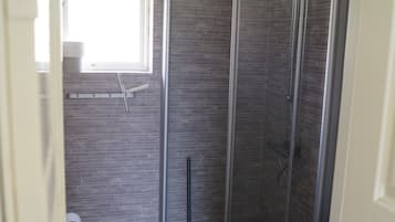 Un bagno con doccia, WC e una finestra.