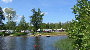 A lakeside campsite with RVs and boats, surrounded by trees and greenery.