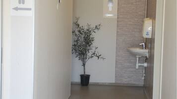 A hallway with a directional sign, a potted plant, a sink, and a sign indicating ladies' facilities.