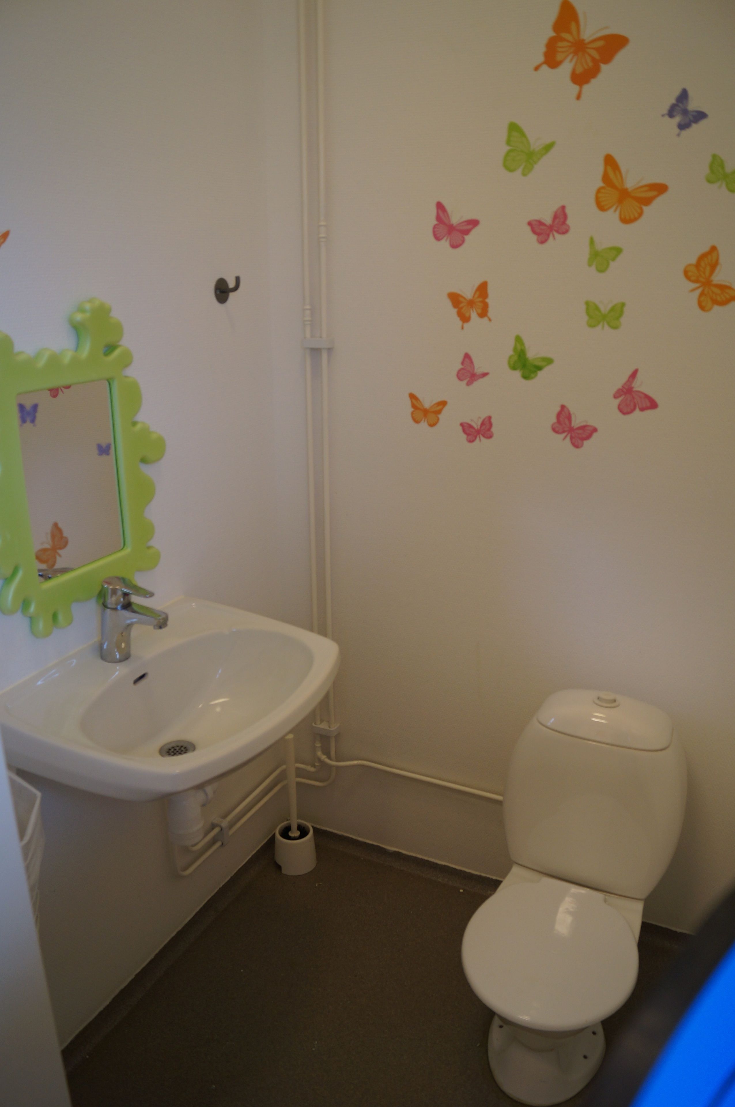 Un bagno con lavandino, specchio, WC e decorazioni murali a forma di farfalla.