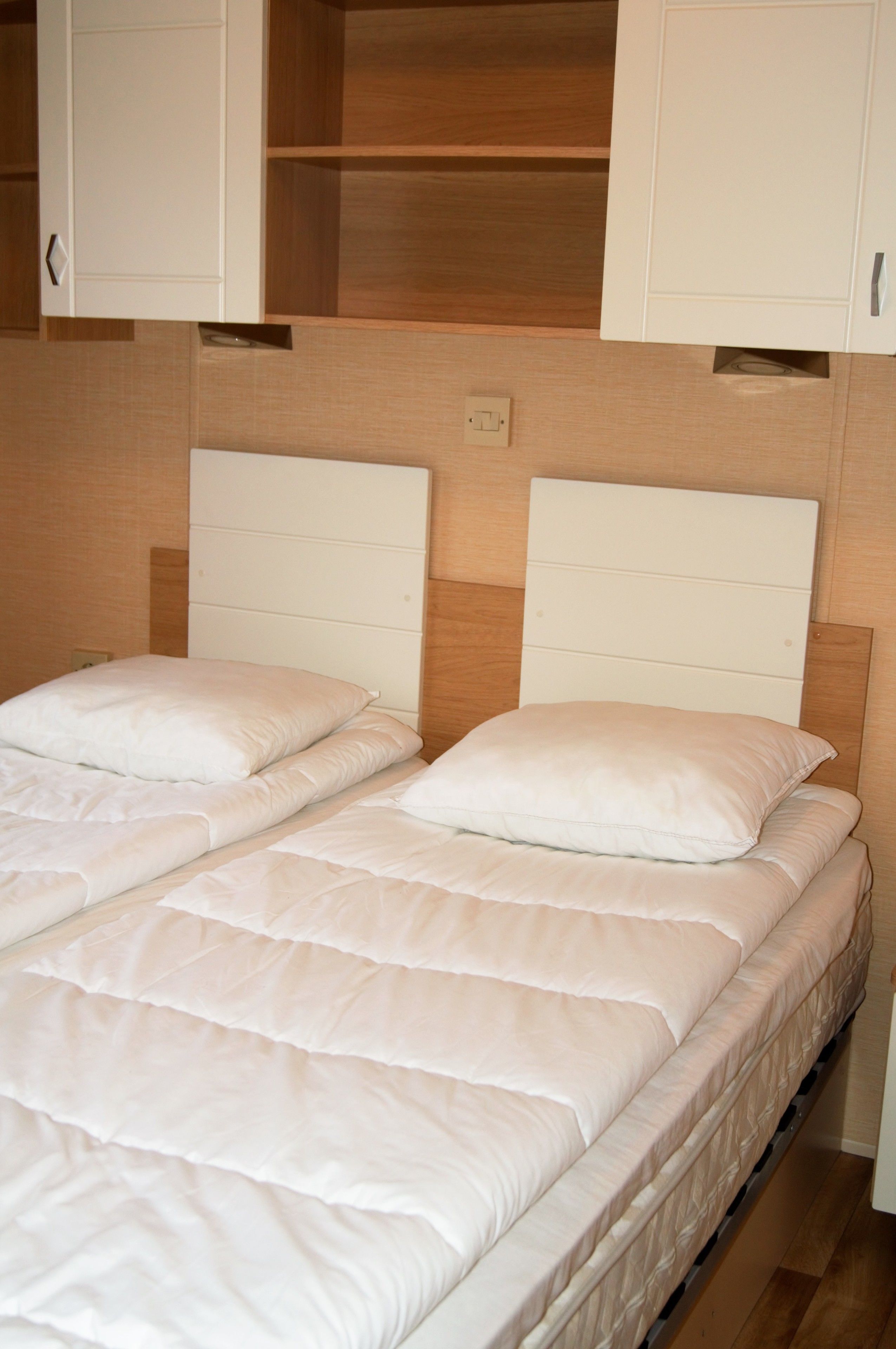 Ein Doppelbett mit Holz Kopfteil und weißer Matratze.