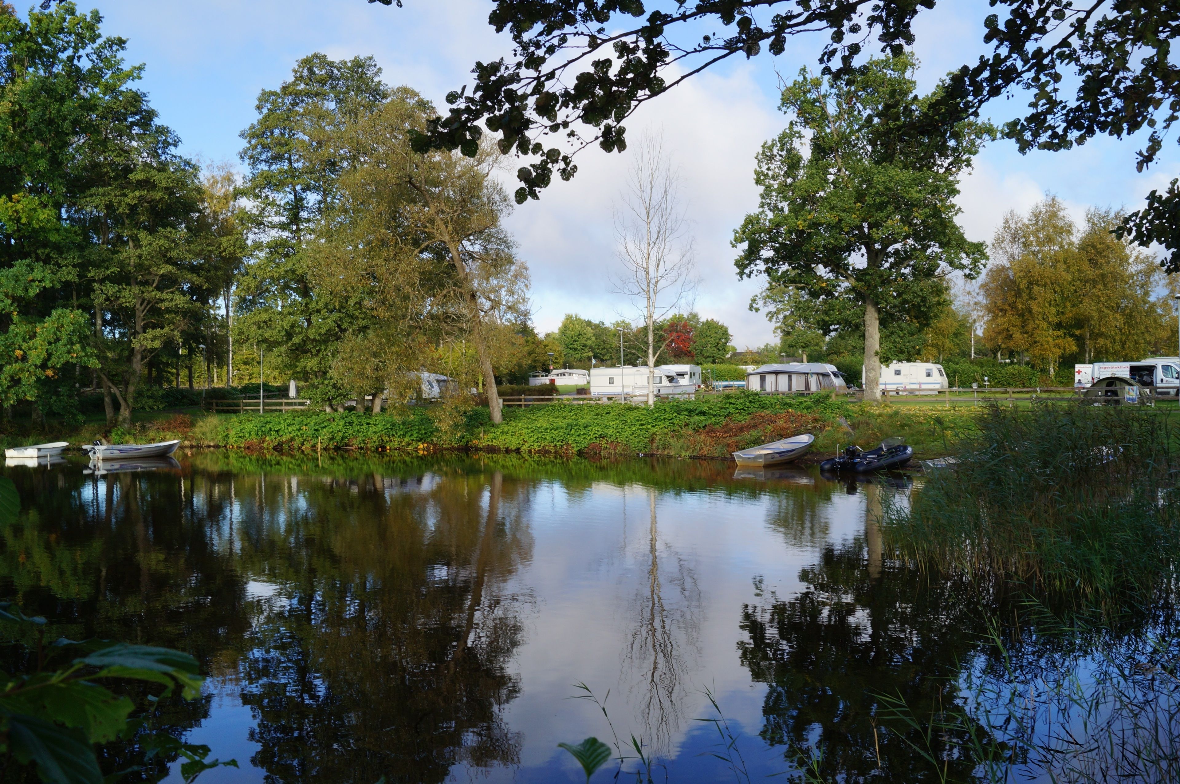 Een rustige kampeerplek aan het meer met campers en boten.